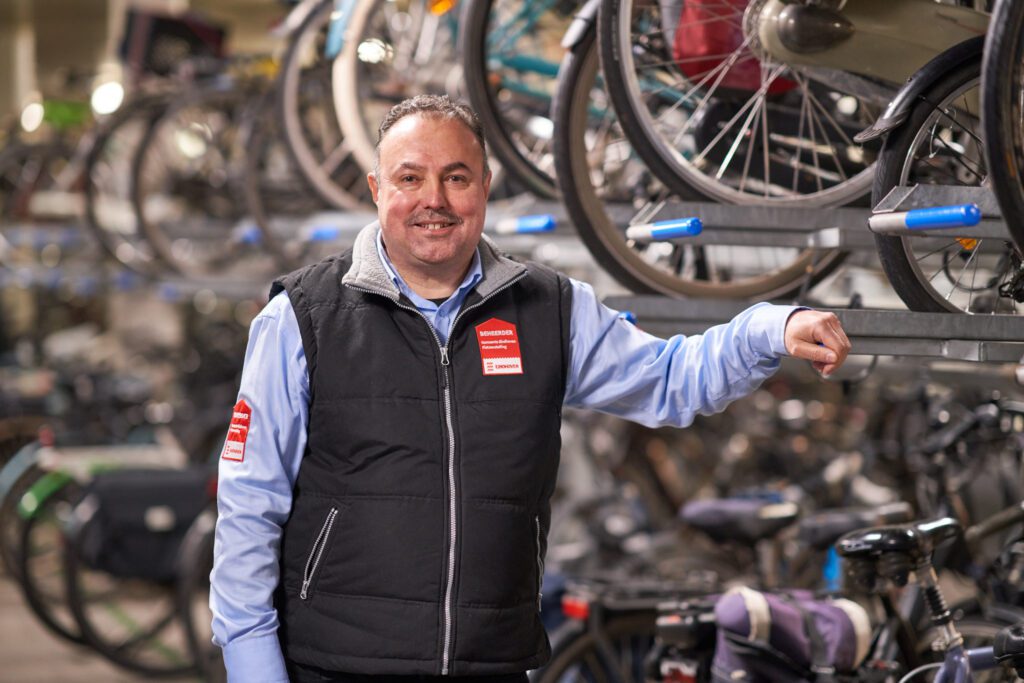 Een medewerker van de fietsenstalling poseert bij een fietsenrek.