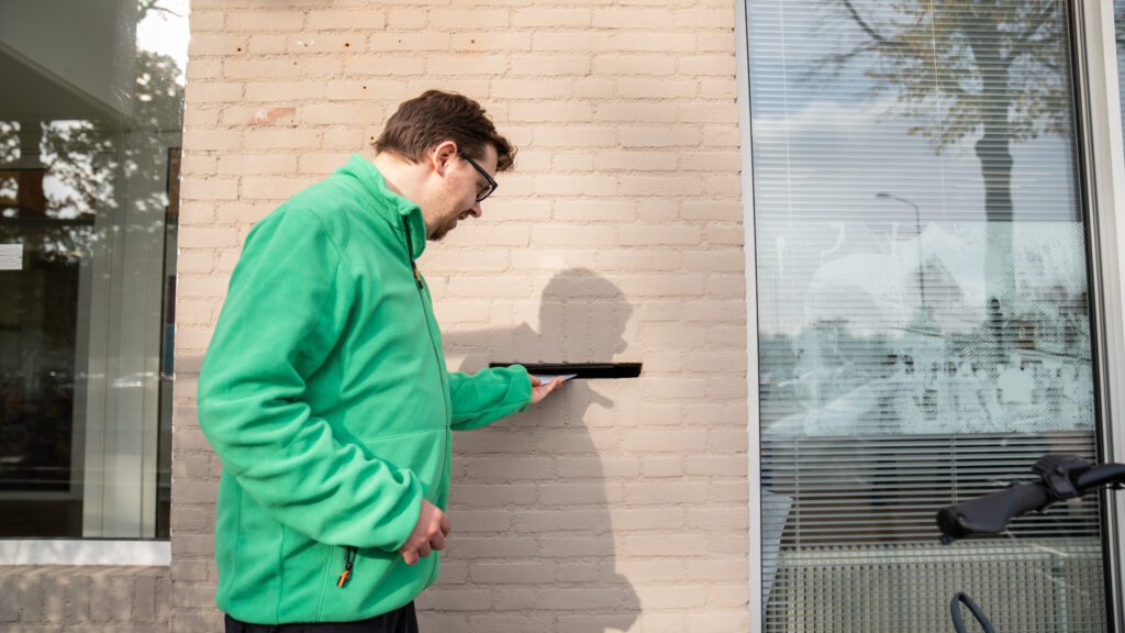 Een postbezorger steekt een brief in een brievenbus.
