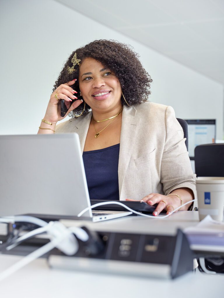 Een medewerker van de Belastingdienst telefoneert achter een bureau.