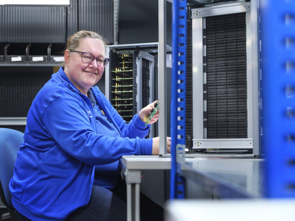 Een medewerker van Bestronics houdt een printplaatje vast in een technische labaratoriumomgeving.