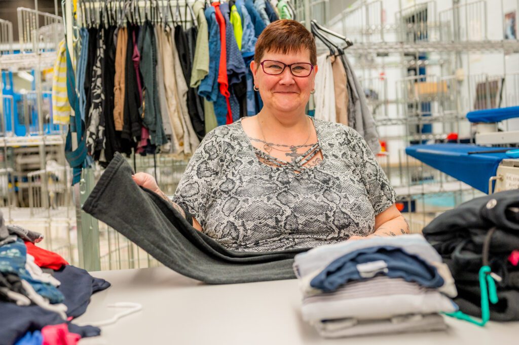 Medewerker vouwt kleding in de Ergon Wasserij