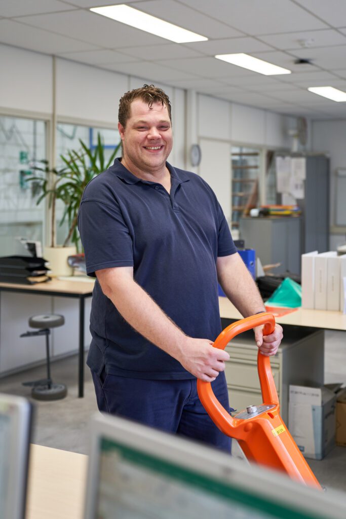 Een medewerker van Ergon Facilitair maakt een kantoor schoon met een schoonmaakmachine die hij met twee handen bedient.