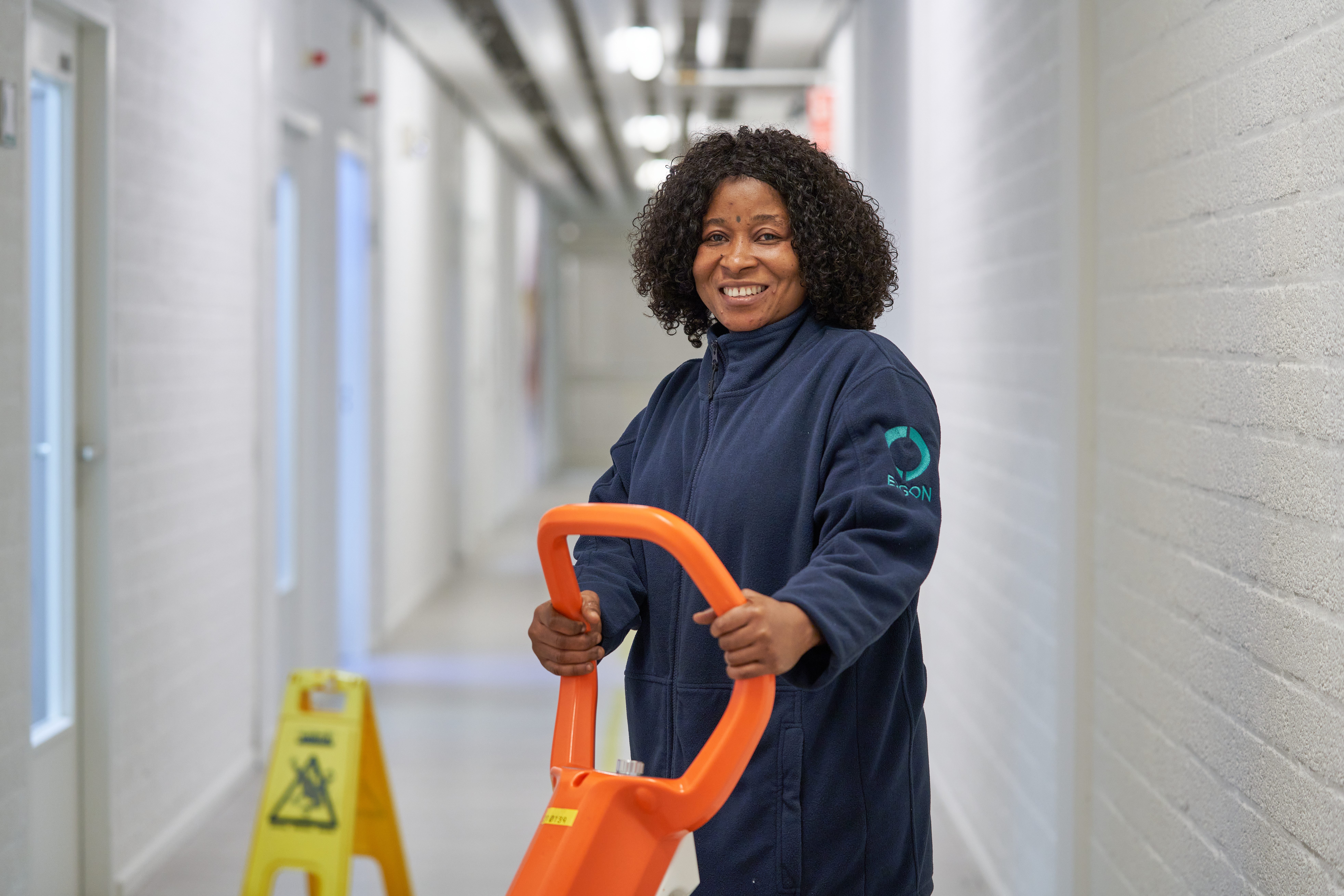 Medewerker van Ergon Facilitair staat met een schoonmaakmachine in een gangpad.