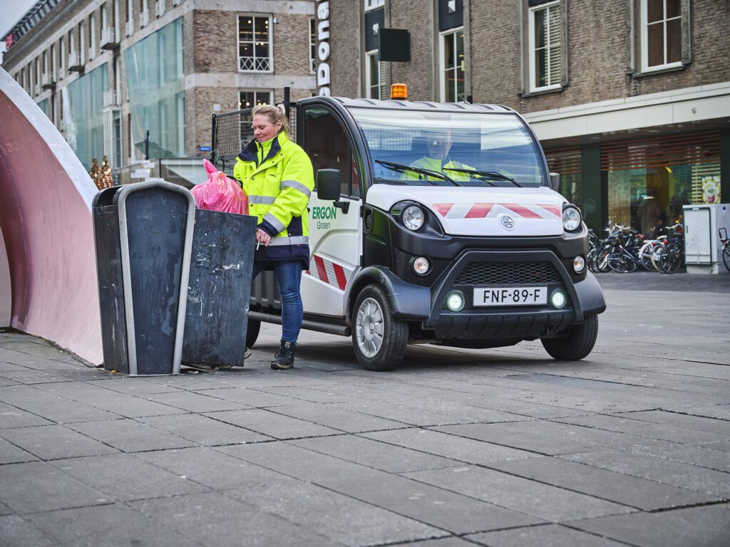 Medewerkers vervangen een prullenbak op het 18 Septemberplein in Eindhoven. Een medewerker vervangt de zak in de prullenbak terwijl de ander wacht in een bakwagen.