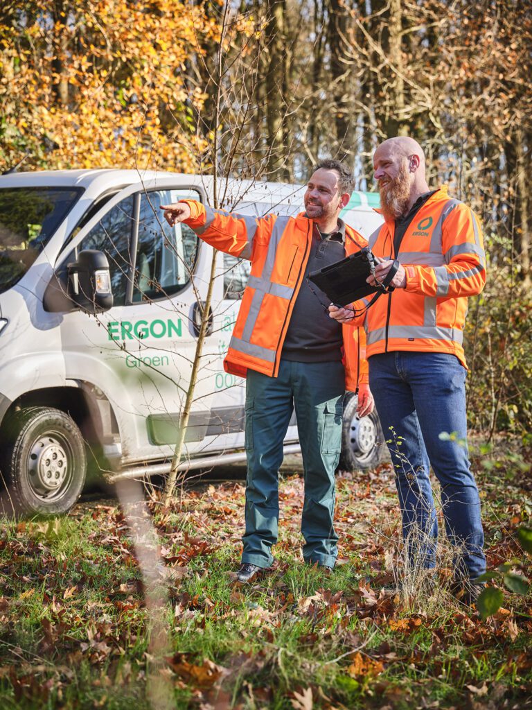 Twee collega's staan in een park naast hun auto te wijzen in de verte