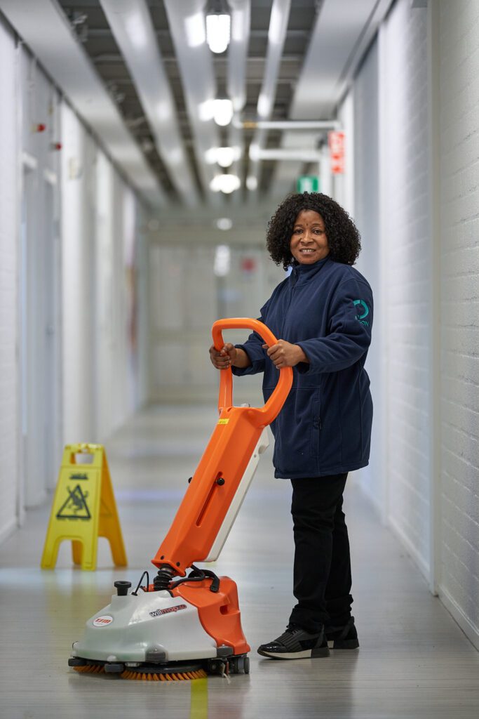 Medewerker van Ergon Facilitair staat met een schoonmaakmachine in een gangpad.