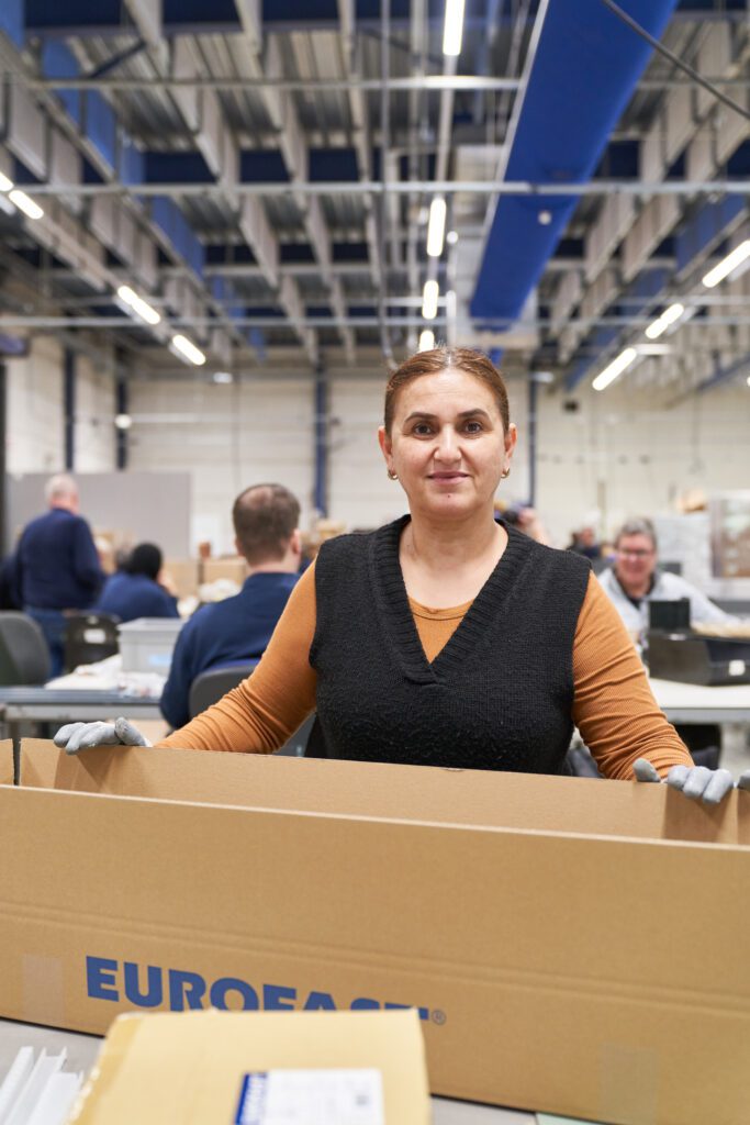 Een medewerker van Ergon Productie vouwt een doos.