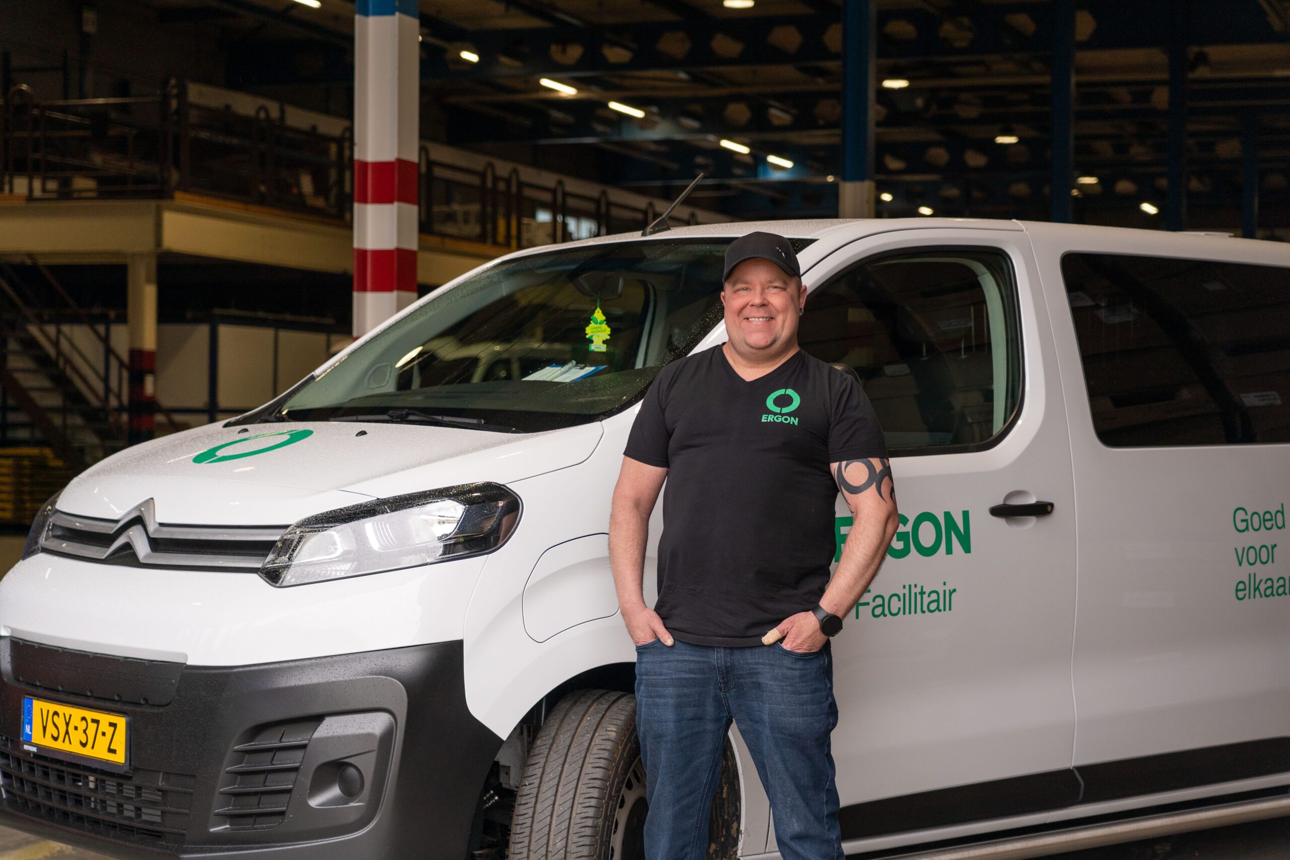 Een medewerker van Ergon Facilitair staat voor een bedrijfswagen.