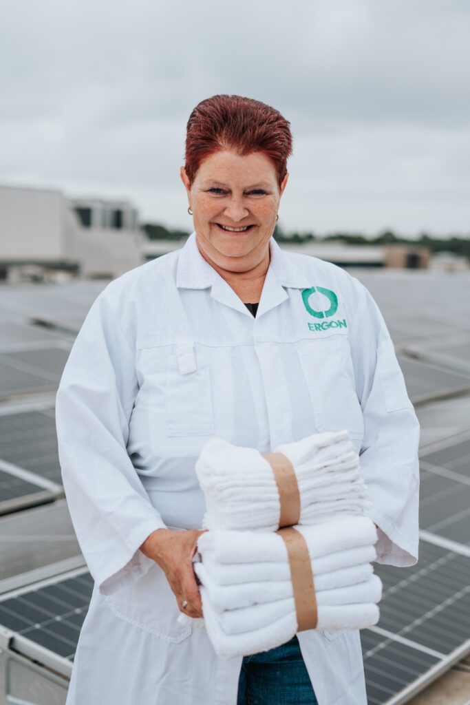 Een medewerker van Ergon Wasserij poseert op een dak vol zonnepanelen.