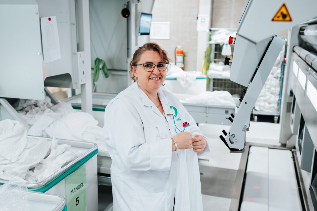 Een medewerker van Ergon Wasserij staat tussen machines.