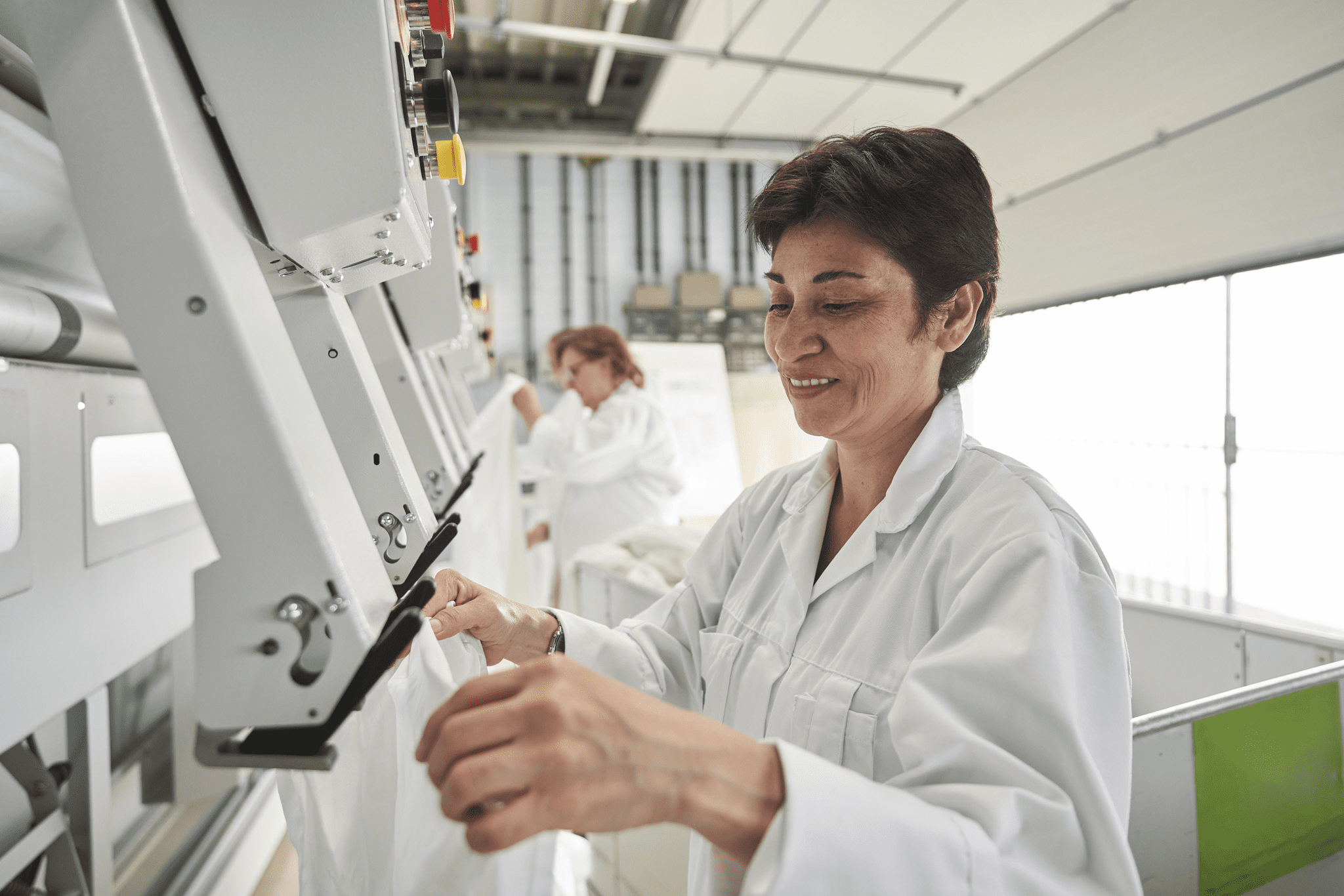 Medewerkers van de wasserij nemen wasgoed uit een machine.