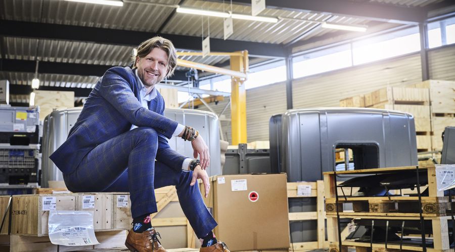 Directeur Stef Visser zit op een kist in een productiehal van Ergon.