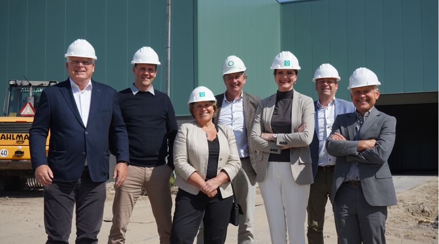 Directie van Ergon en Cleanlease vieren de samenwerking en poseren voor een fabriekshal.