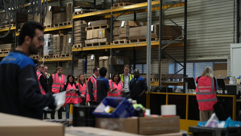 Minister staat met groep medewerkers Ergon in het magazijn