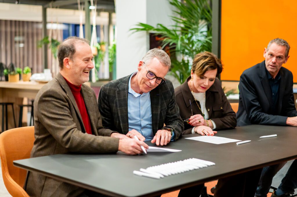 Bestuurders tekenen het convenant aan tafel.