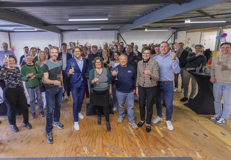 Groep genodigden proosten met glas champagne op de opening